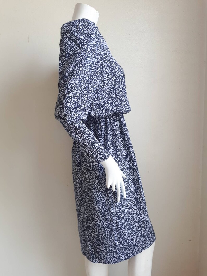 May include: A blue and white floral print dress with long sleeves and a gathered waist.