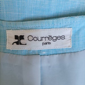 May include: A white label with black text that reads "Courr&egrave;ges Paris" on a light blue fabric background.