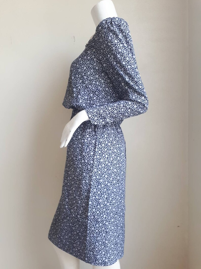 May include: A blue and white floral print dress with long sleeves and a gathered waist.