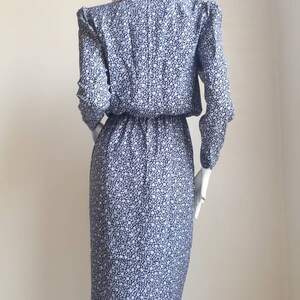 May include: A blue and white floral print dress with a white lace collar. The dress has long sleeves and a fitted silhouette.