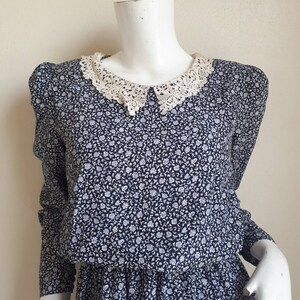 May include: A vintage floral dress with a white lace collar. The dress has a fitted bodice and a gathered skirt. The fabric is a lightweight cotton blend.