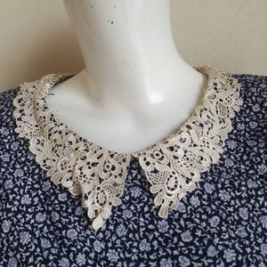 May include: A blue and white floral print dress with a white lace collar.
