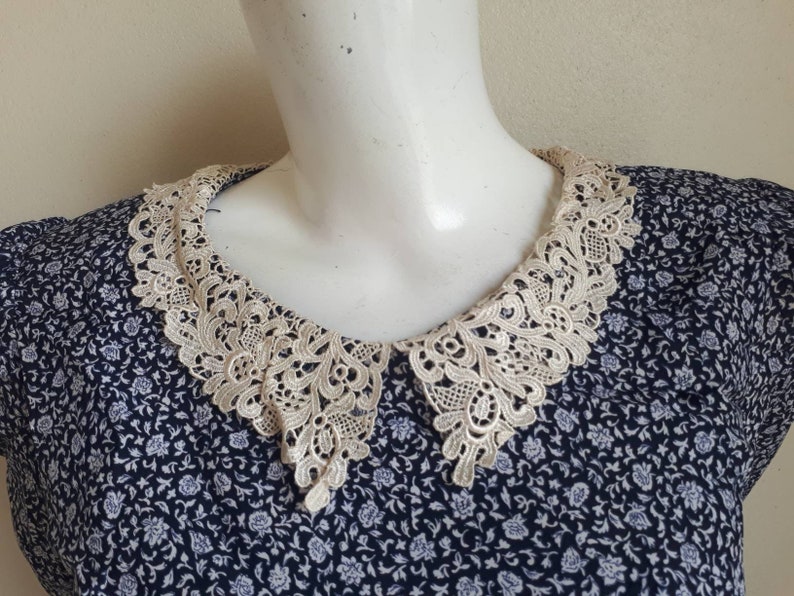 May include: A blue and white floral print dress with a white lace collar.