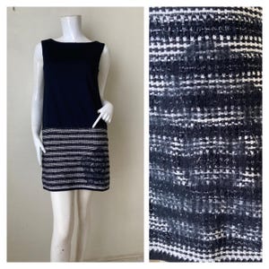 Könnte beinhalten: Ein schwarzes und weißes ärmelloses Kleid mit schwarzem Oberteil und einem weißen und schwarzen gestreiften Unterteil. Das Kleid ist aus einem strukturierten Stoff.