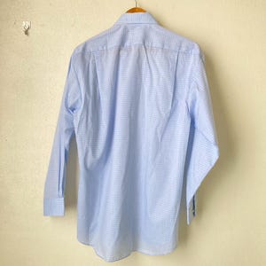 May include: A light blue long-sleeved button-down shirt with a white and light blue checkered pattern.