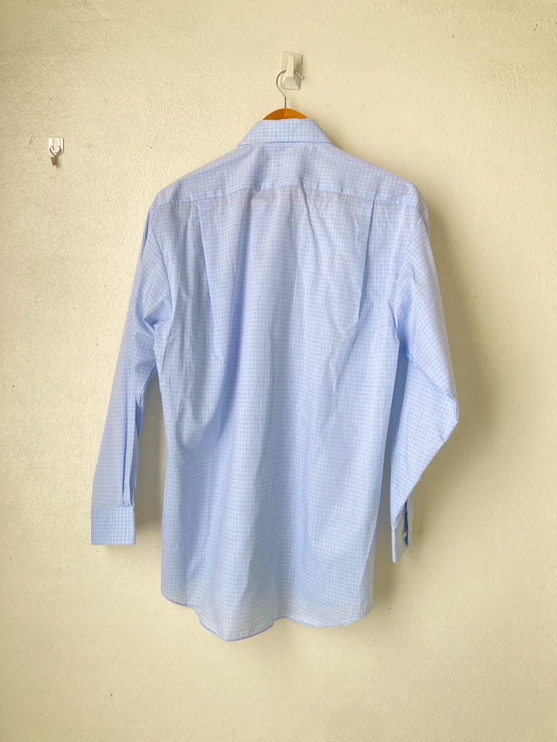 May include: A light blue long-sleeved button-down shirt with a white and light blue checkered pattern.