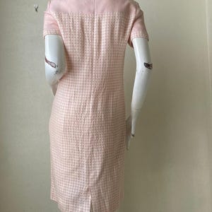 May include: A pink and white gingham dress with short sleeves. The dress has a fitted bodice and a slightly flared skirt.