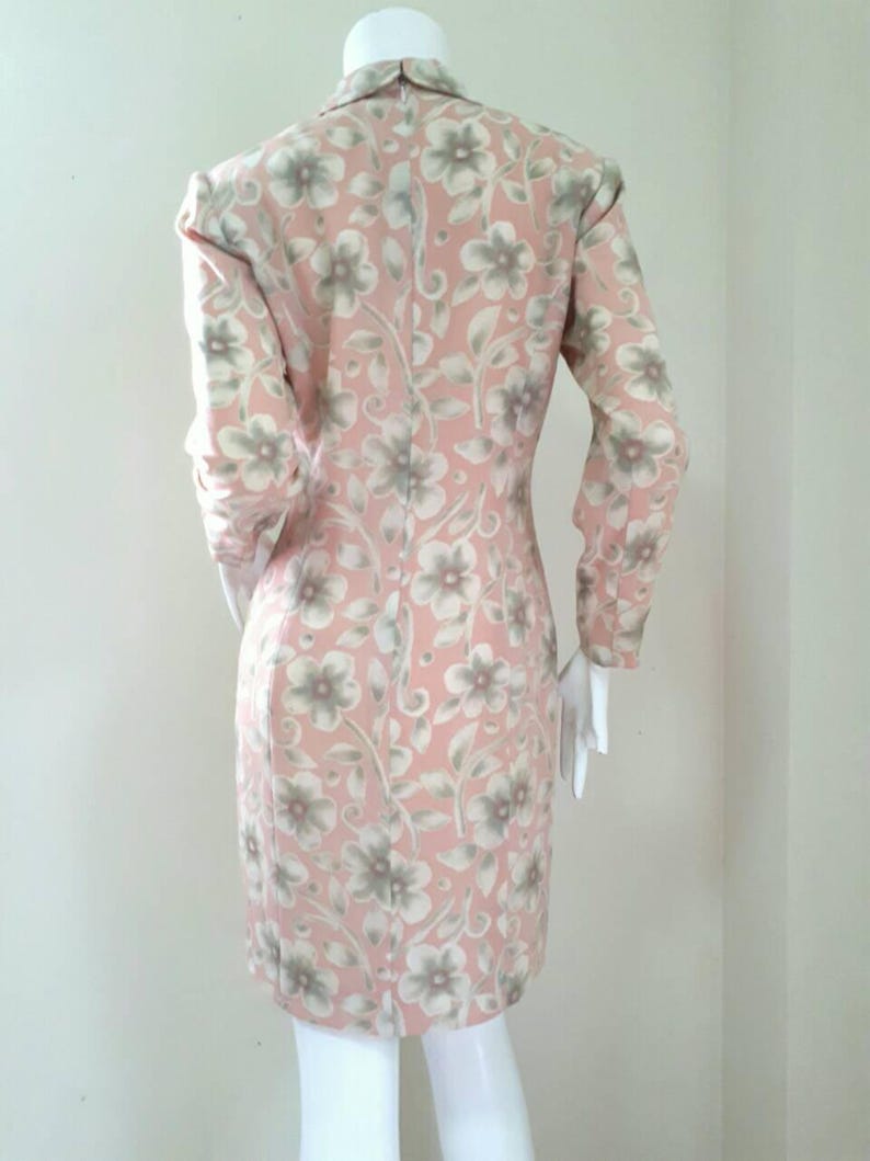 May include: A pink dress with a floral pattern. The dress has long sleeves and a fitted silhouette.
