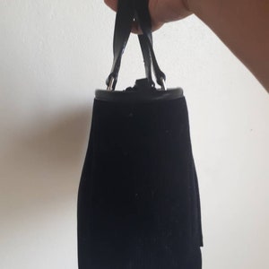 K&ouml;nnte beinhalten: Eine schwarze Samt-Handtasche mit einem Henkel oben und silbernen Beschl&auml;gen.