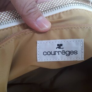 May include: A beige fabric bag with a white zipper and a white label that says "Courr&egrave;ges" in black text.