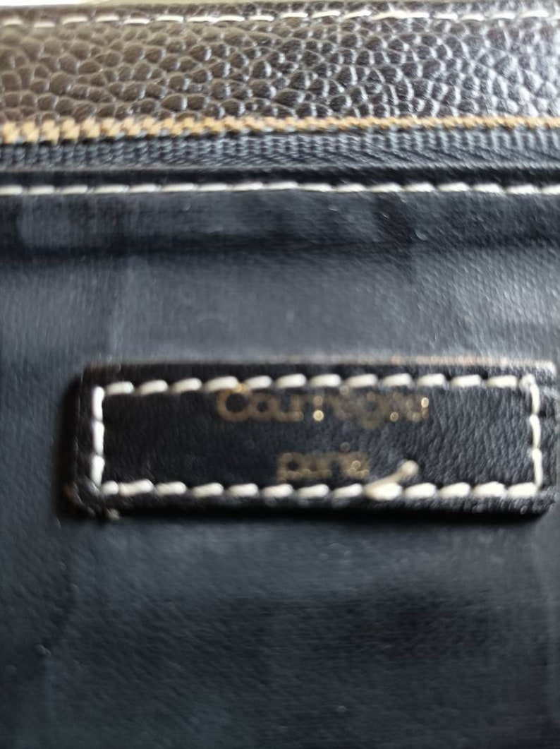May include: Close-up of a black leather wallet with white stitching. The wallet has a small label that reads "Courr&egrave;ges Paris".