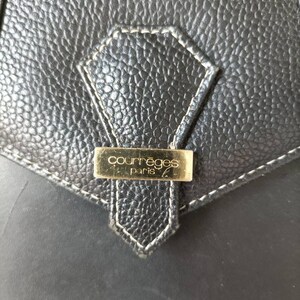 May include: Close-up of a black leather purse with a gold metal tag that reads "Courr&egrave;ges Paris".