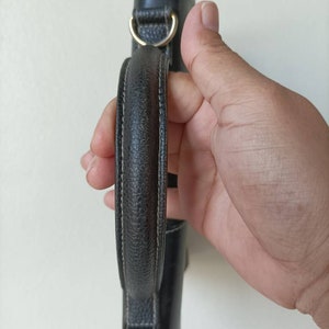 May include: A black leather handbag with a top handle and gold hardware.