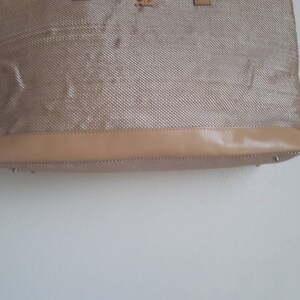 May include: A beige tote bag with a woven texture and a brown leather trim.