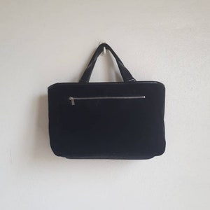 K&ouml;nnte beinhalten: Eine schwarze Samt-Tragetasche mit Rei&szlig;verschluss und schwarzen Ledergriffen.