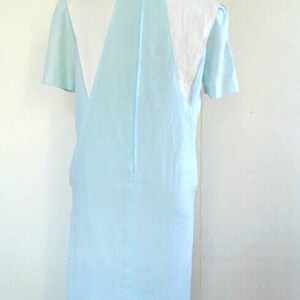 May include: A light blue dress with a white collar and short sleeves. The dress is on a mannequin.