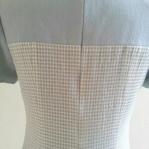 May include: A light blue dress with a white and light blue checkered pattern. The dress has a zipper in the back.
