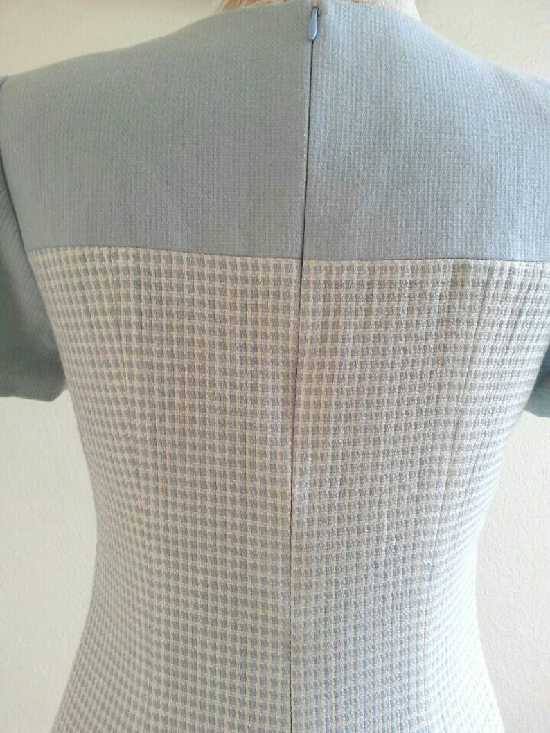 May include: A light blue dress with a white and light blue checkered pattern. The dress has a zipper in the back.
