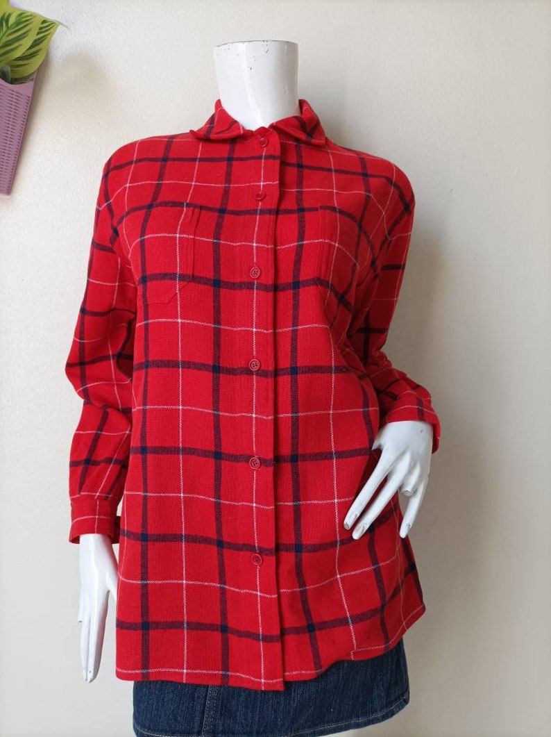 May include: A red and blue plaid long-sleeved shirt with a button-up front and two chest pockets.