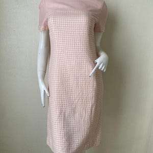 May include: A pink and white houndstooth dress with short sleeves and a fitted silhouette.