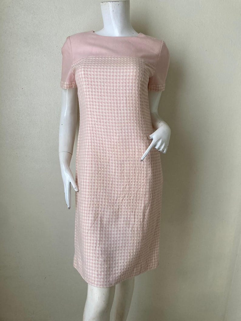 May include: A pink and white houndstooth dress with short sleeves and a fitted silhouette.