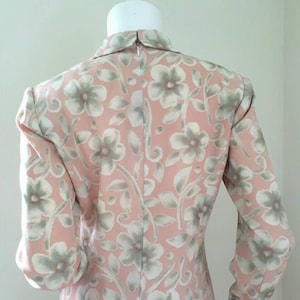 May include: A pink dress with a floral pattern in shades of green and white. The dress has long sleeves and a collared neckline.