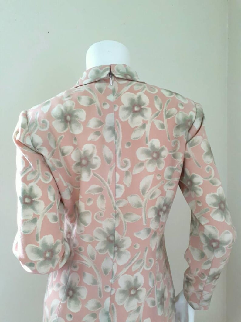 May include: A pink dress with a floral pattern in shades of green and white. The dress has long sleeves and a collared neckline.