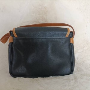May include: A black leather shoulder bag with brown trim. The bag has a flap closure and a single strap.