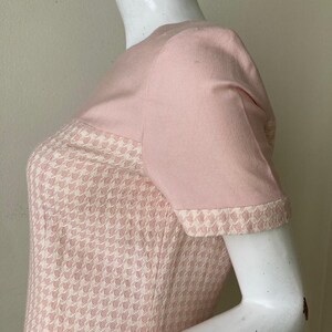May include: A pink and white houndstooth dress with short sleeves. The dress has a solid pink bodice and a houndstooth skirt.