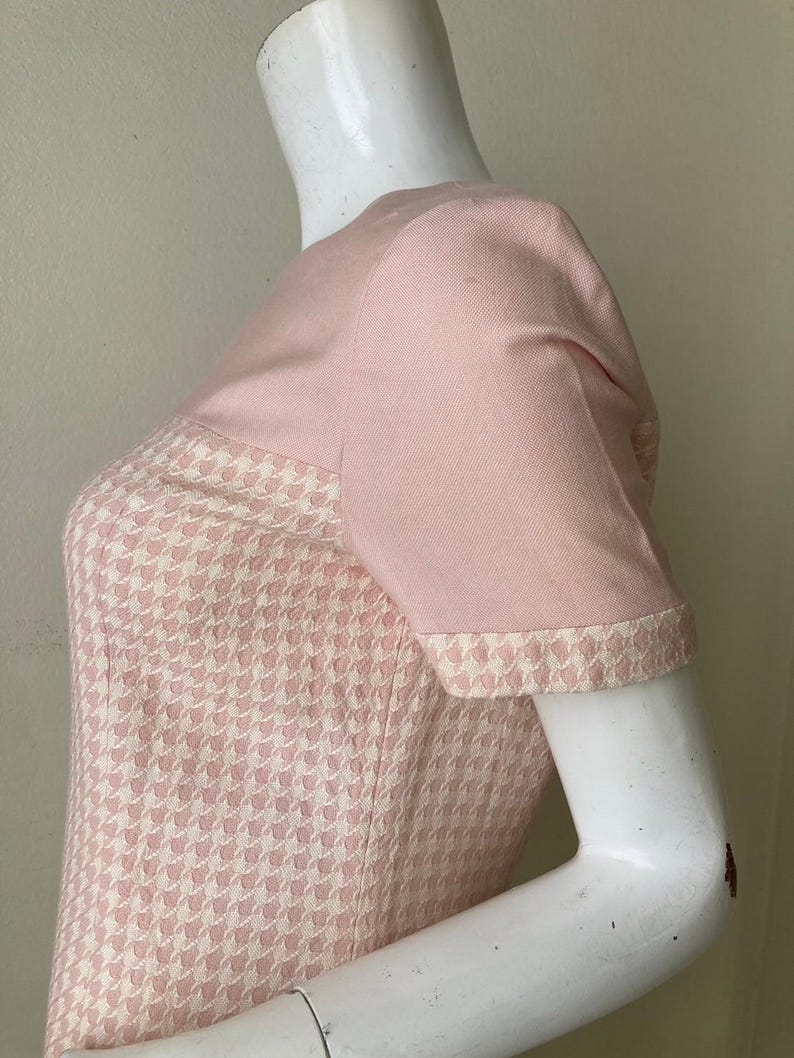 May include: A pink and white houndstooth dress with short sleeves. The dress has a solid pink bodice and a houndstooth skirt.