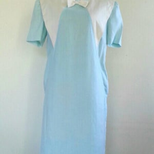May include: A light blue dress with a white collar and a bow. The dress has short sleeves and a straight silhouette.