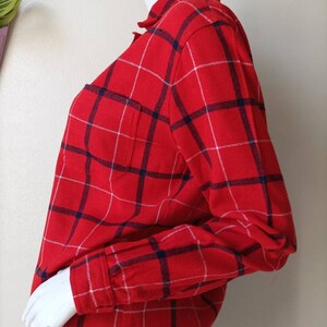 May include: Red and blue plaid long-sleeve shirt with a white pocket.