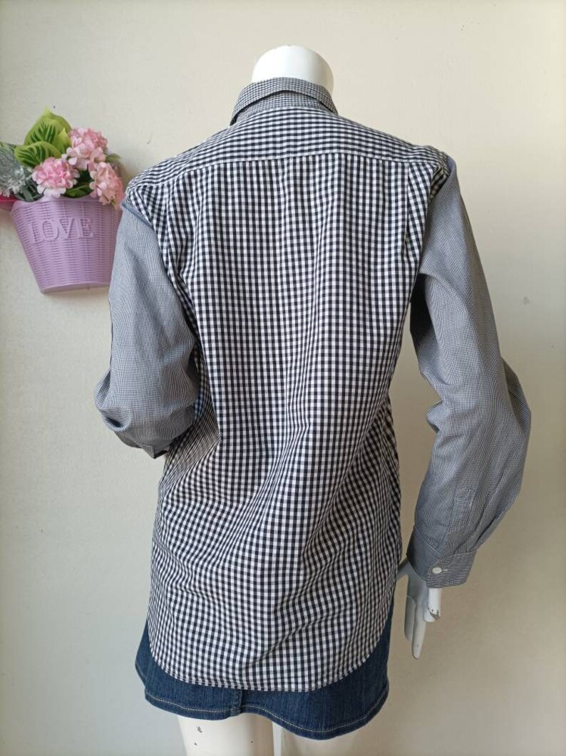 May include: A long-sleeved button-down shirt with a black and white gingham pattern. The shirt has a contrasting gray and white gingham pattern on the sleeves.