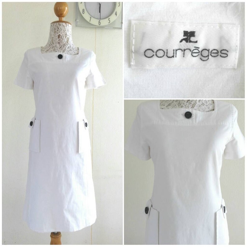 May include: White short-sleeved dress with black buttons and pockets. The dress has a square neckline and the label reads "Courr&egrave;ges".