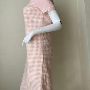 May include: A pink and white gingham dress with short sleeves. The dress has a fitted bodice and a slightly flared skirt.