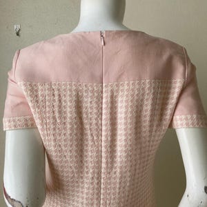 May include: A pink dress with a houndstooth pattern. The dress has short sleeves and a zipper in the back.