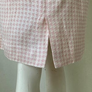 May include: A pink and white gingham skirt with a back slit.