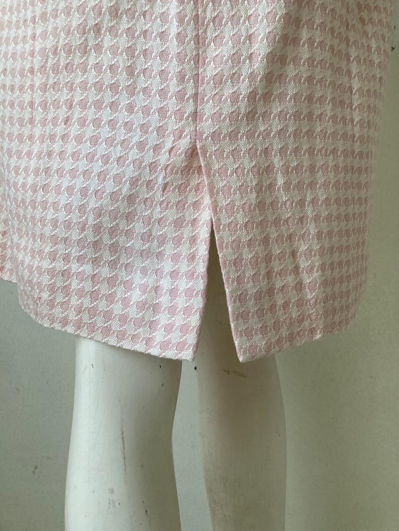 May include: A pink and white gingham skirt with a back slit.