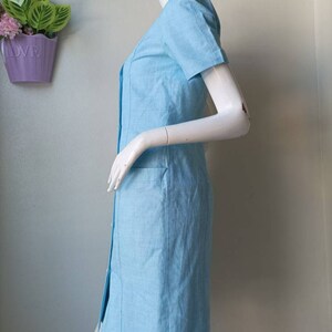 May include: A light blue short-sleeved dress with a button-up front and a pocket on the side.