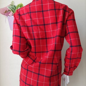 May include: Red and white plaid long-sleeve shirt with blue trim. The shirt has a button-down collar and a relaxed fit.