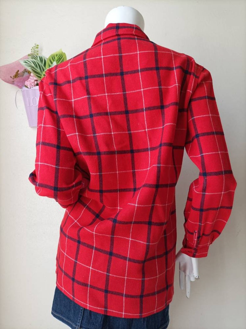 May include: Red and white plaid long-sleeve shirt with blue trim. The shirt has a button-down collar and a relaxed fit.
