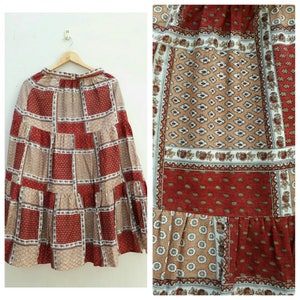 May include: A long, tiered skirt with a patchwork design. The skirt is made of a cotton fabric and features a variety of brown, red, and white patterns.