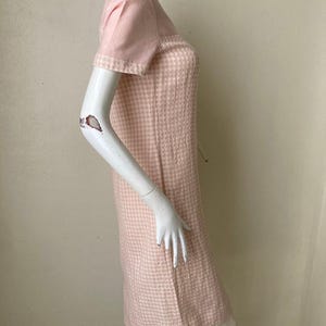 May include: A pink and white gingham dress with short sleeves. The dress has a fitted bodice and a slightly flared skirt.