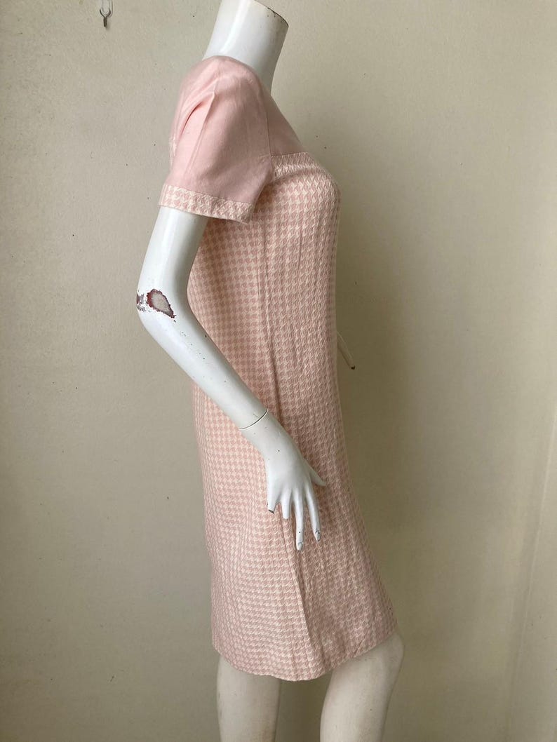 May include: A pink and white gingham dress with short sleeves. The dress has a fitted bodice and a slightly flared skirt.
