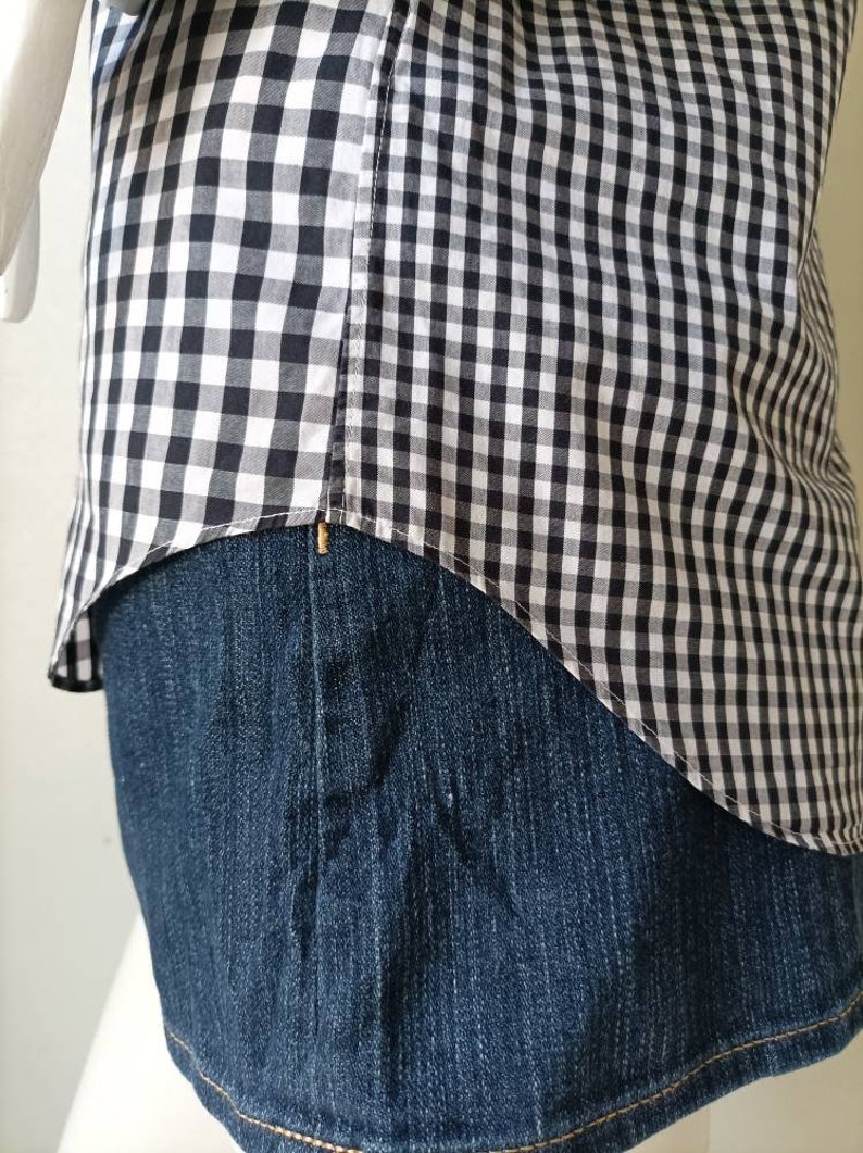 May include: A black and white gingham shirt tucked into a pair of blue denim jeans.