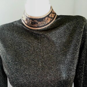 May include: A black long-sleeved shirt with a gold and black patterned turtleneck.
