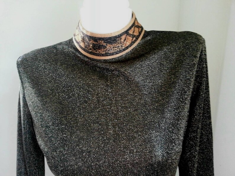 May include: A black long-sleeved shirt with a gold and black patterned turtleneck.