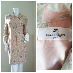 May include: A pink and white floral print dress with long sleeves and a collared neckline. The dress has a button closure and a label that reads "Courr&egrave;ges Paris".