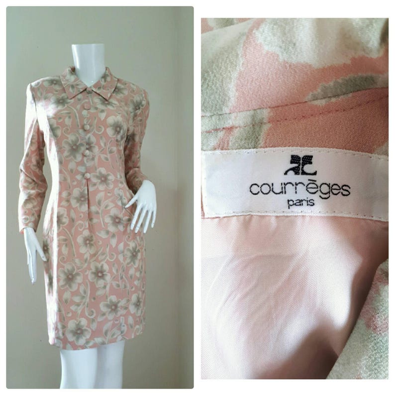 May include: A pink and white floral print dress with long sleeves and a collared neckline. The dress has a button closure and a label that reads "Courr&egrave;ges Paris".