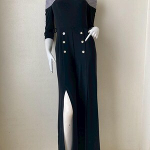 May include: Black off-the-shoulder jumpsuit with a high slit. The top features a striped pattern and long sleeves. The front has decorative buttons. The jumpsuit is displayed on a mannequin.